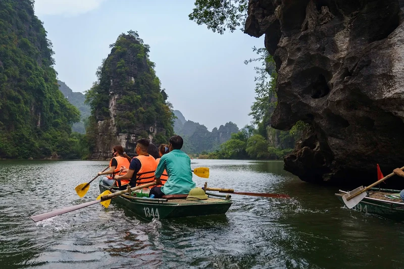 A quiet moment on the Trang An river as boats glide out from the cave into open scenery Trang an boat tour ninh binh
